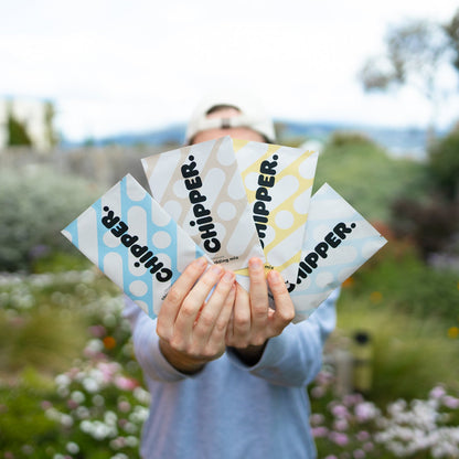 Person holding multiple 'Chipper' product packages outdoors with a garden background